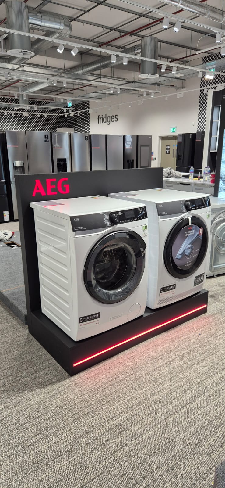AEG washing machine and dryer display with red LED base lighting at Harvey Norman